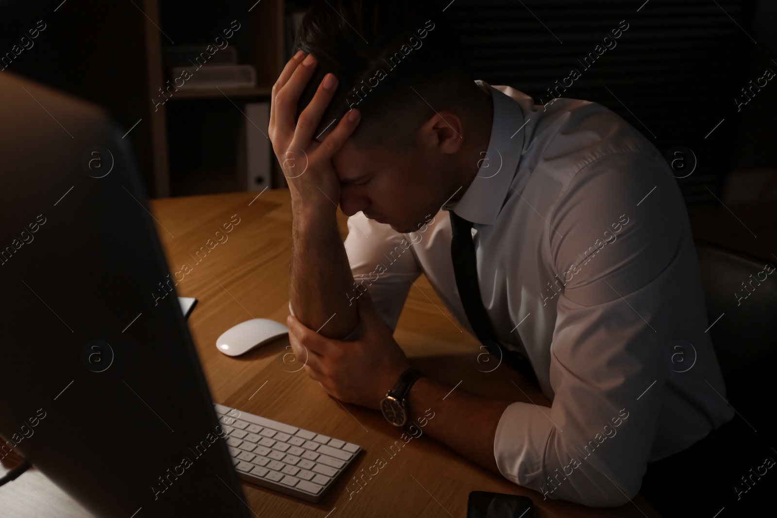 Photo of Businessman stressing out at workplace late in evening