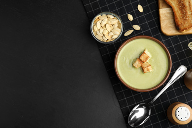 Photo of Delicious broccoli cream soup with croutons served on black table, flat lay. Space for text
