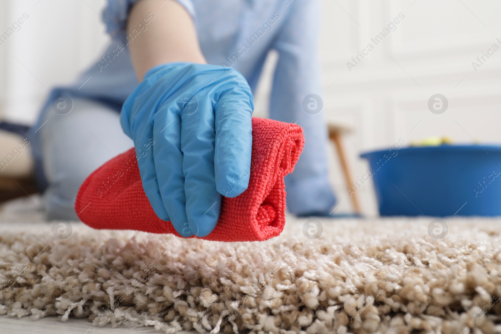 Photo of Woman in rubber gloves cleaning carpet with rag indoors, closeup. Space for text