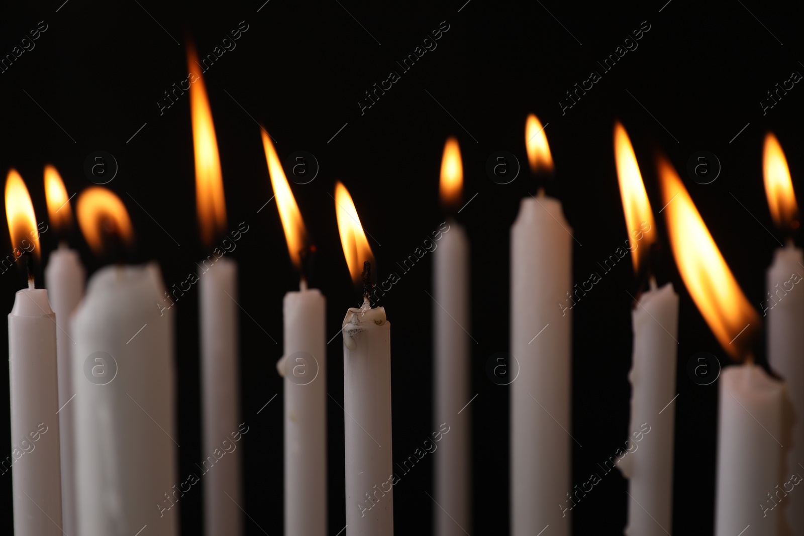 Photo of Many burning church candles on black background