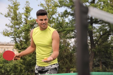 Photo of Happy man playing ping pong outdoors on summer day