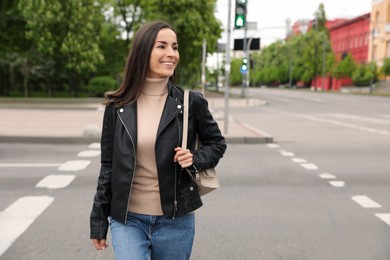 Photo of Young woman crossing street. Traffic rules and regulations