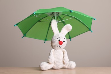 Small umbrella and toy bunny on wooden table