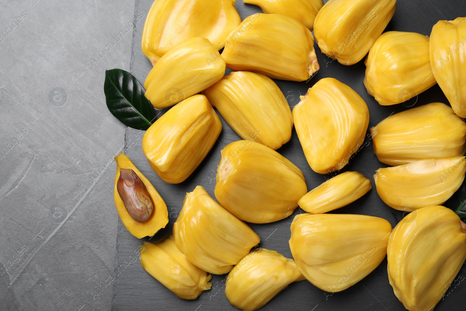 Photo of Delicious exotic jackfruit bulbs on grey table, top view