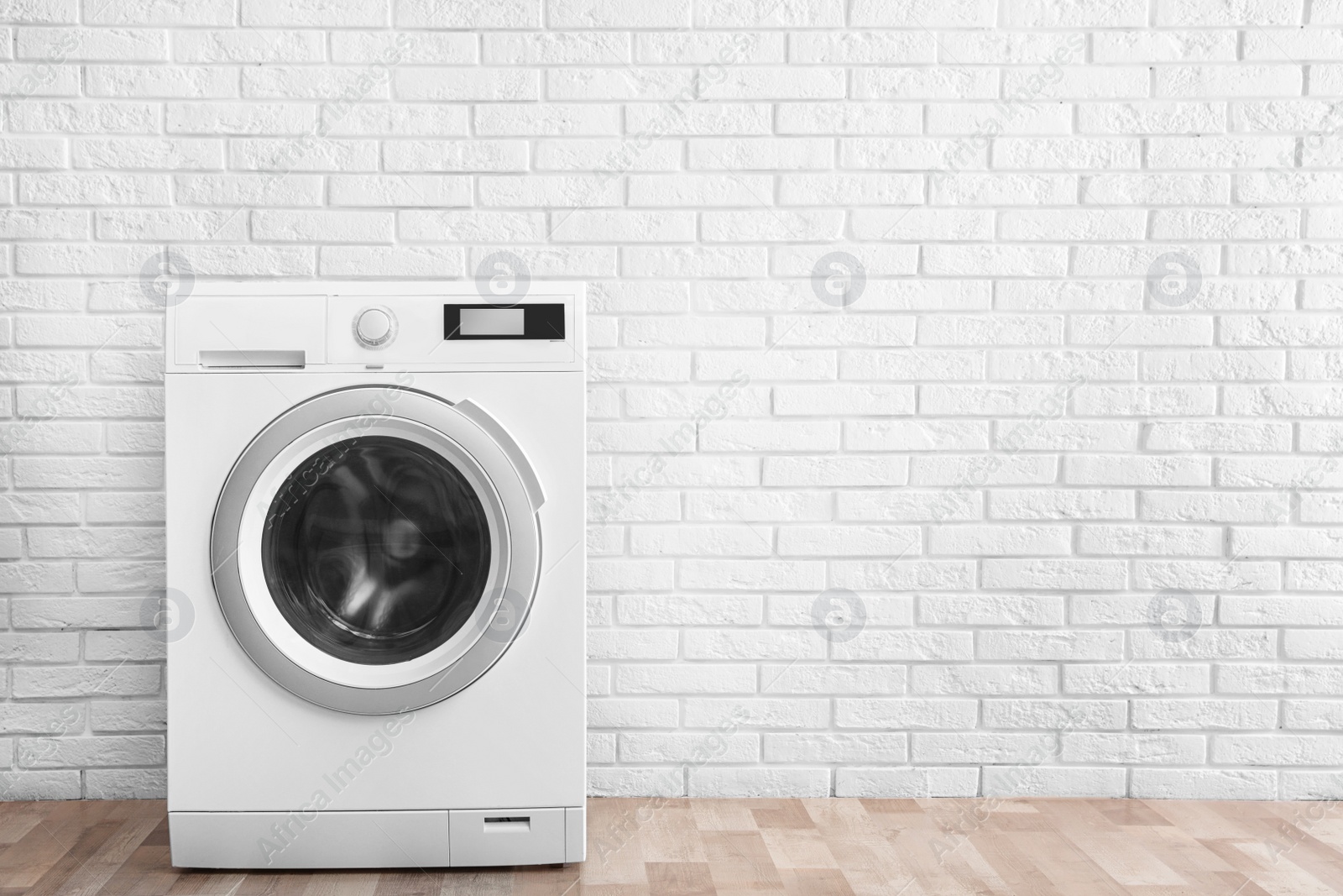 Photo of Modern washing machine near brick wall in empty laundry room, space for text