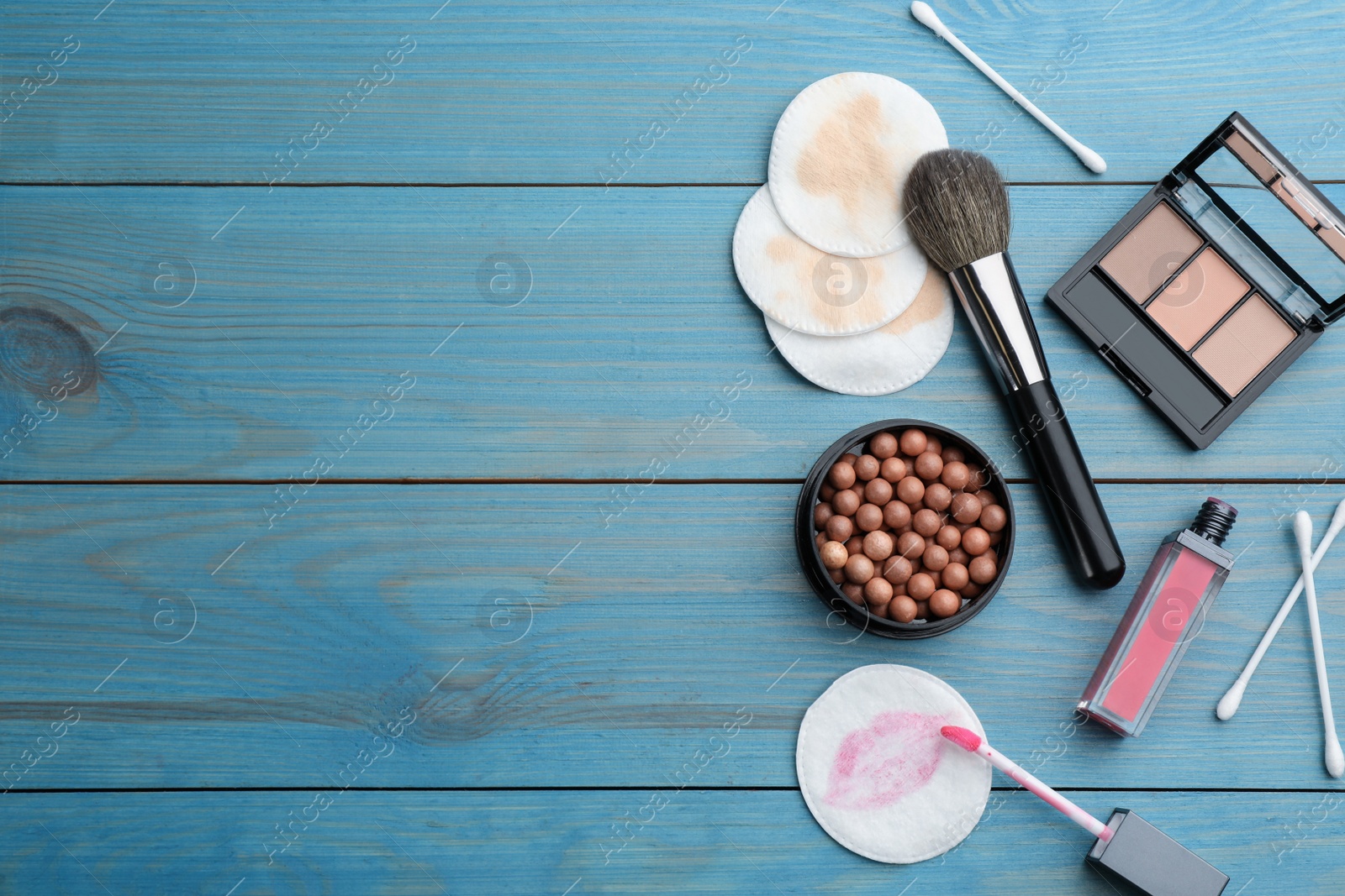 Photo of Dirty cotton pads, swabs and cosmetic products on blue wooden background, flat lay. Space for text