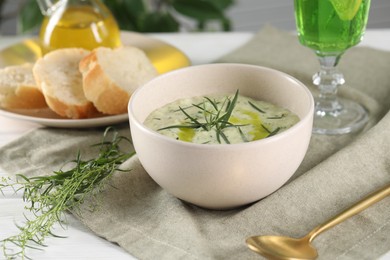 Photo of Delicious cream soup with tarragon, spices and potato in bowl served on white table