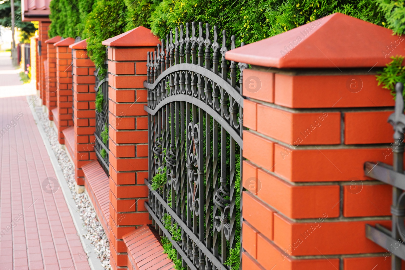 Photo of Beautiful brick fence with iron railing outdoors