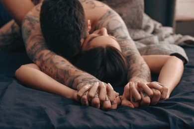 Photo of Passionate couple having sex on bed, focus on hands