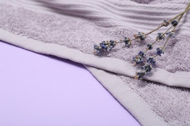 Photo of Terry towel and lavender flowers on violet background, closeup. Space for text