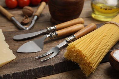 Cheese knives and fork on wooden board, closeup. Cooking utensils
