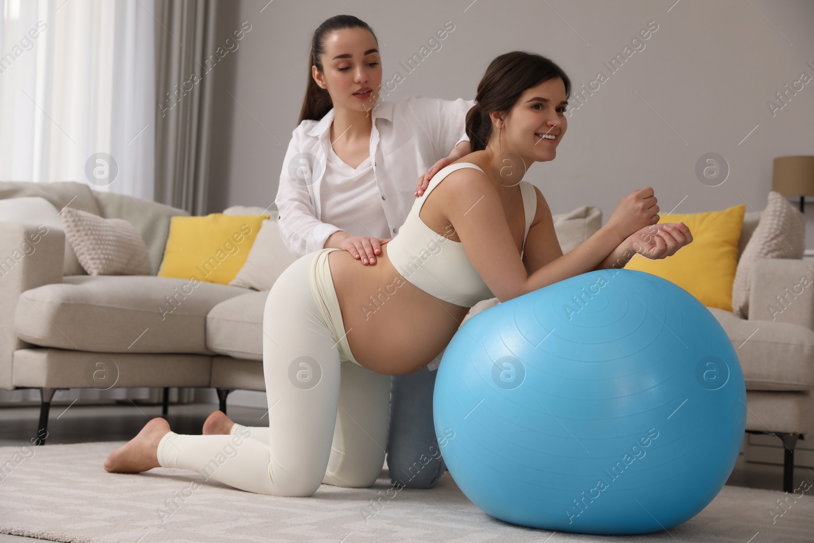 Photo of Doula working with pregnant woman in living room. Preparation for child birth