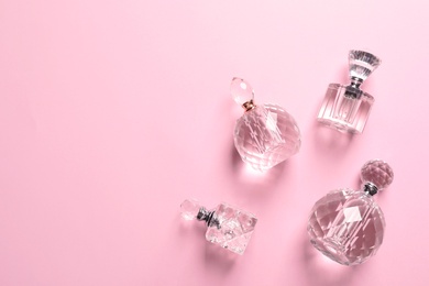 Photo of Flat lay composition with bottles of perfume and space for text on pink background