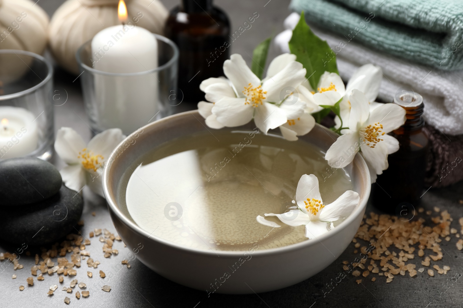 Photo of Beautiful spa composition with jasmine essential oil and fresh flowers on grey table, closeup