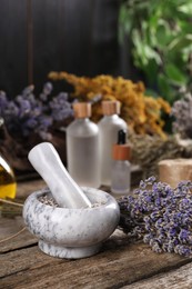 Photo of Mortar with pestle and lavender flowers on wooden table, closeup. Medicinal herbs