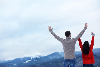 Photo of Couple enjoying mountain landscape, space for text. Winter vacation