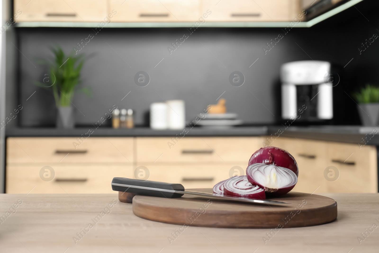 Photo of Board with fresh onion and knife on wooden table in kitchen