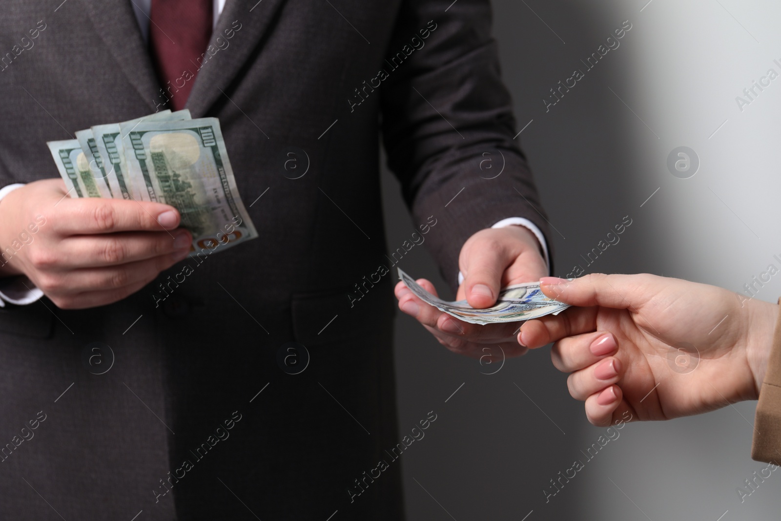 Photo of Man giving money to woman on light grey background, closeup. Currency exchange