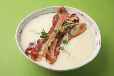 Photo of Delicious potato soup with bacon and microgreens on green background