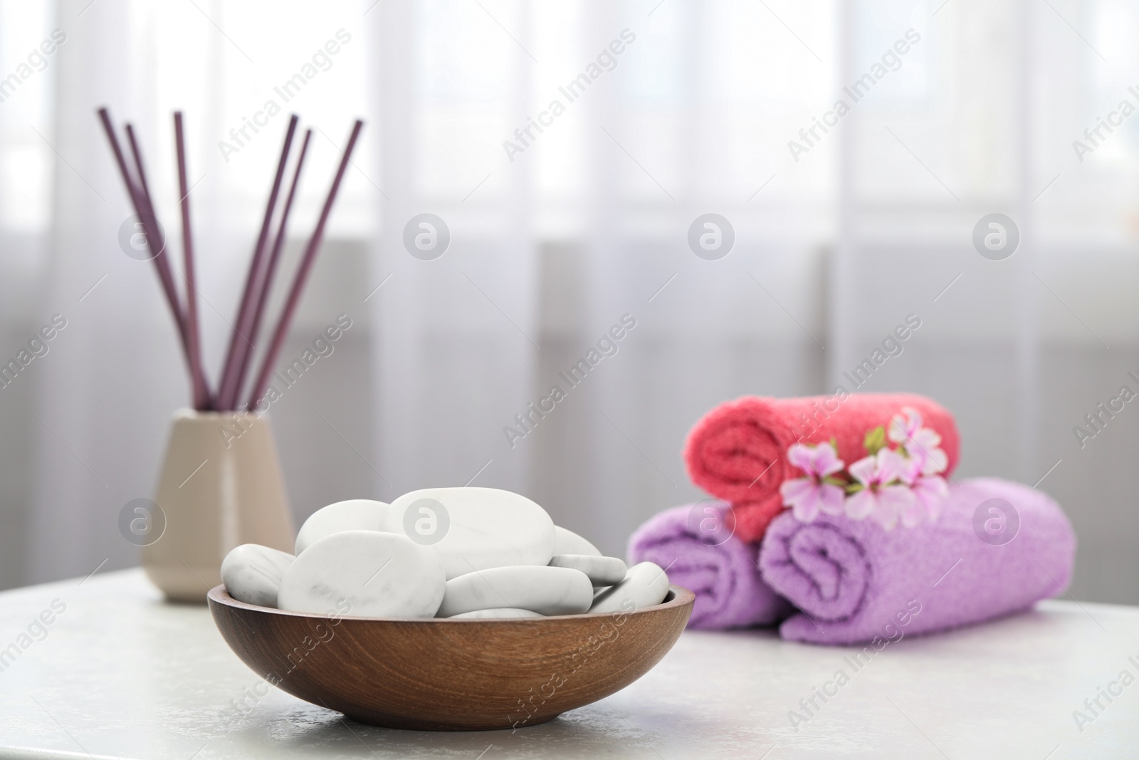 Photo of Spa stones, towels and reed freshener on white table indoors