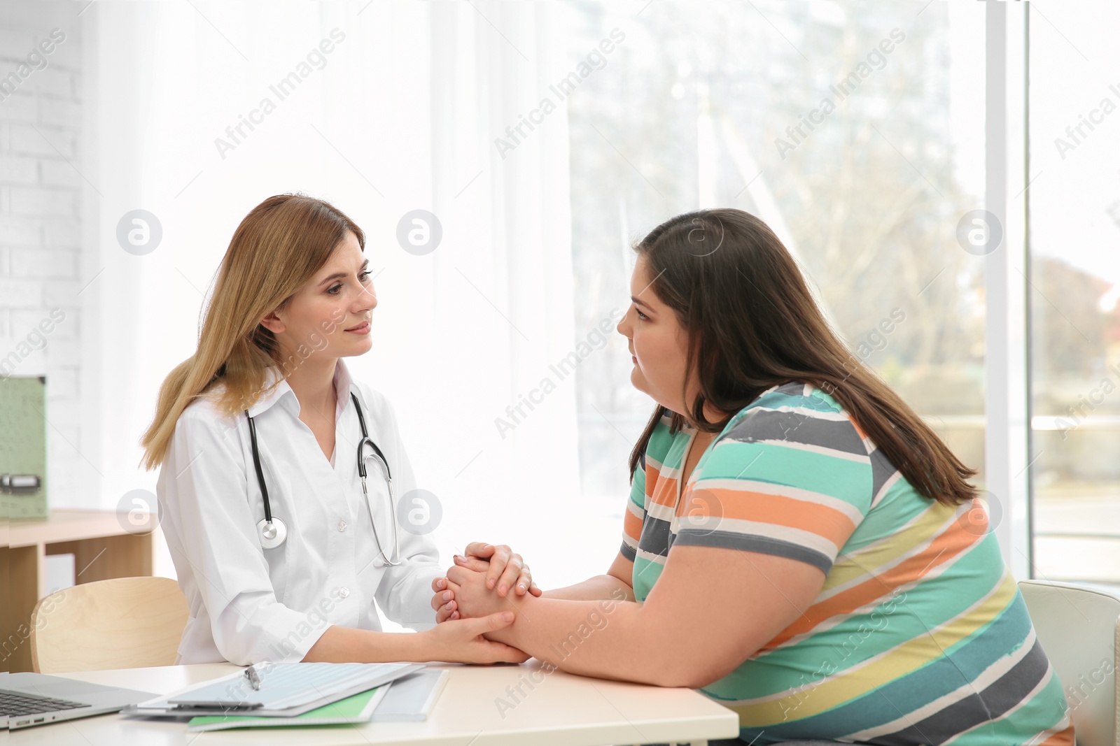 Photo of Female doctor consulting overweight woman in clinic