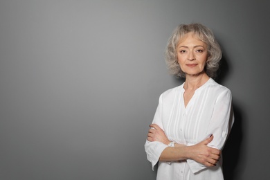 Portrait of mature woman on grey background. Space for text