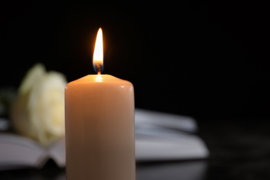 Burning candle on blurred background, space for text. Funeral symbol