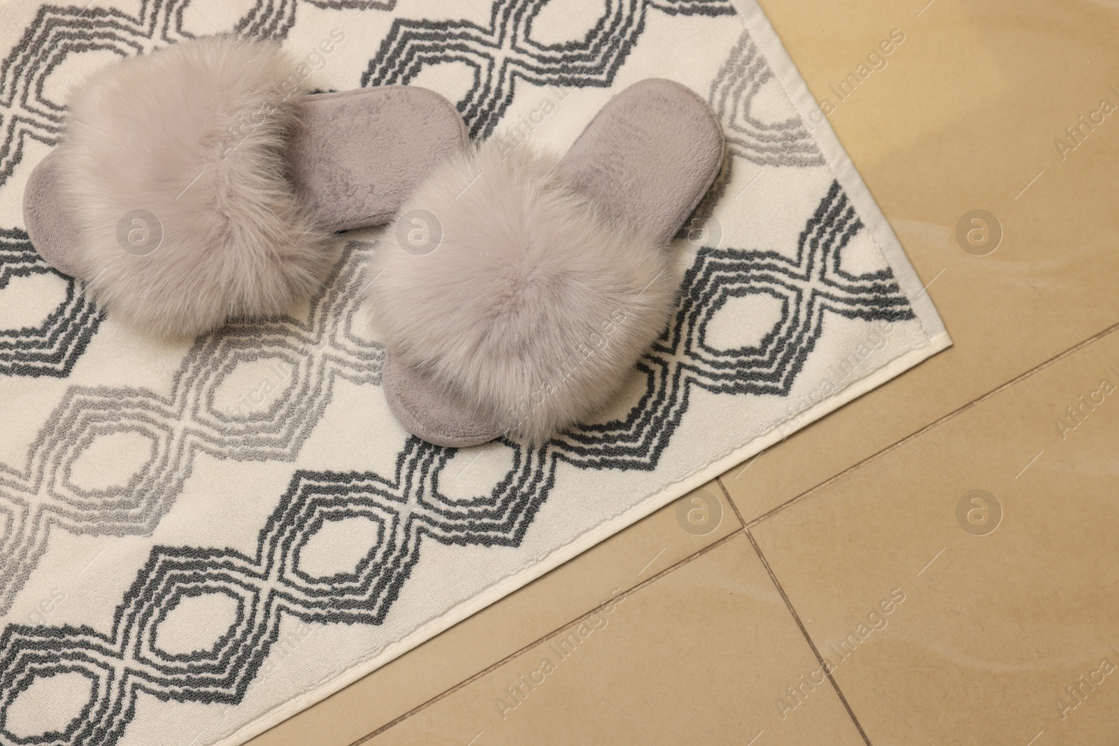 Photo of Soft bath mat and slippers on floor, top view