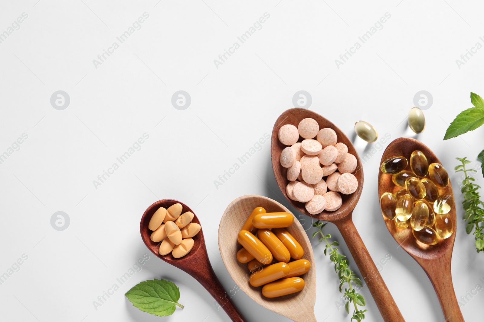 Photo of Different pills and herbs on white background, flat lay with space for text. Dietary supplements