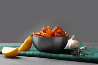 Photo of Composition with bowl of sweet potato chips on table against grey background. Space for text