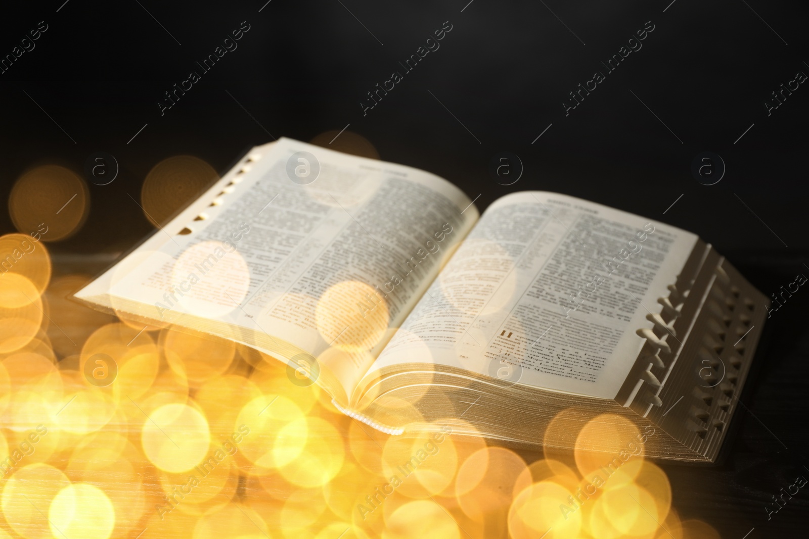 Image of Open Bible on black table, bokeh effect