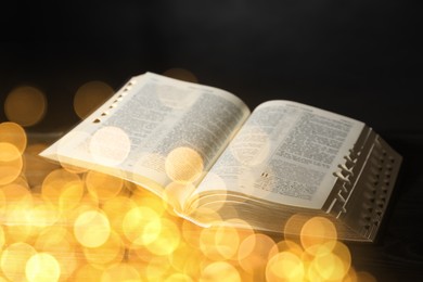 Image of Open Bible on black table, bokeh effect