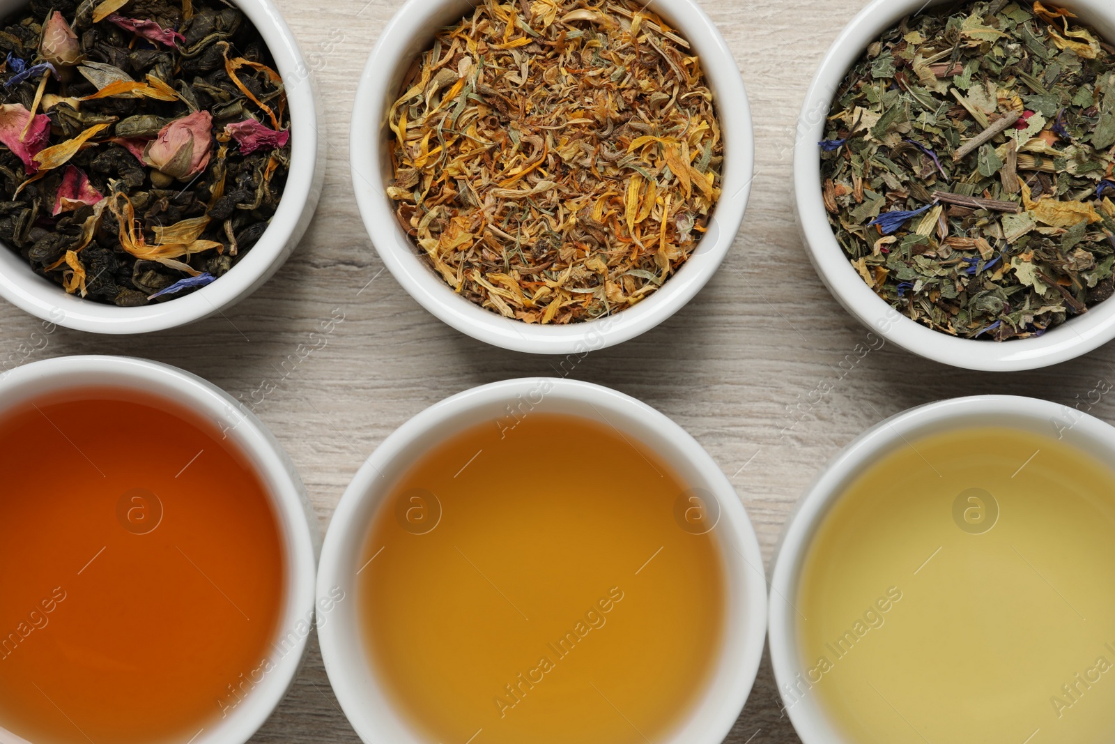 Photo of Flat lay composition with different freshly brewed teas and dry leaves on wooden table