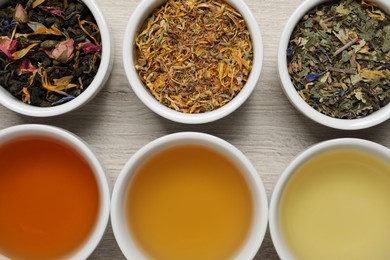 Flat lay composition with different freshly brewed teas and dry leaves on wooden table