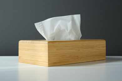 Photo of Wooden holder with paper tissues on white table