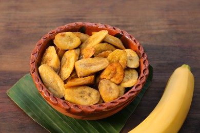 Photo of Tasty deep fried banana slices and fresh fruit on wooden table