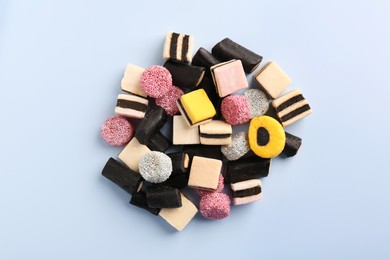 Photo of Many tasty liquorice candies on light blue background, top view