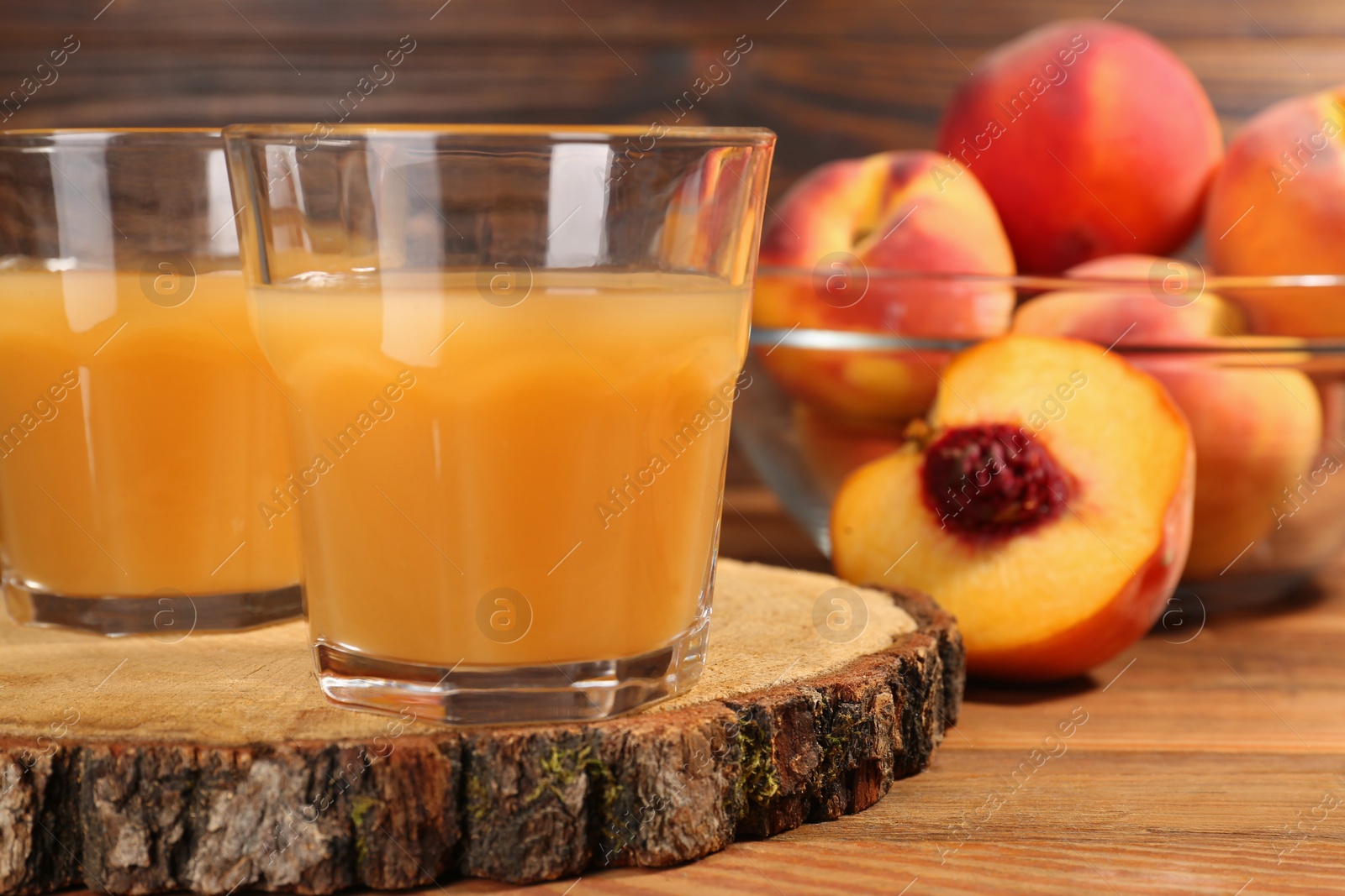 Photo of Glasses of delicious peach juice and fresh fruits on wooden table, closeup. Space for text