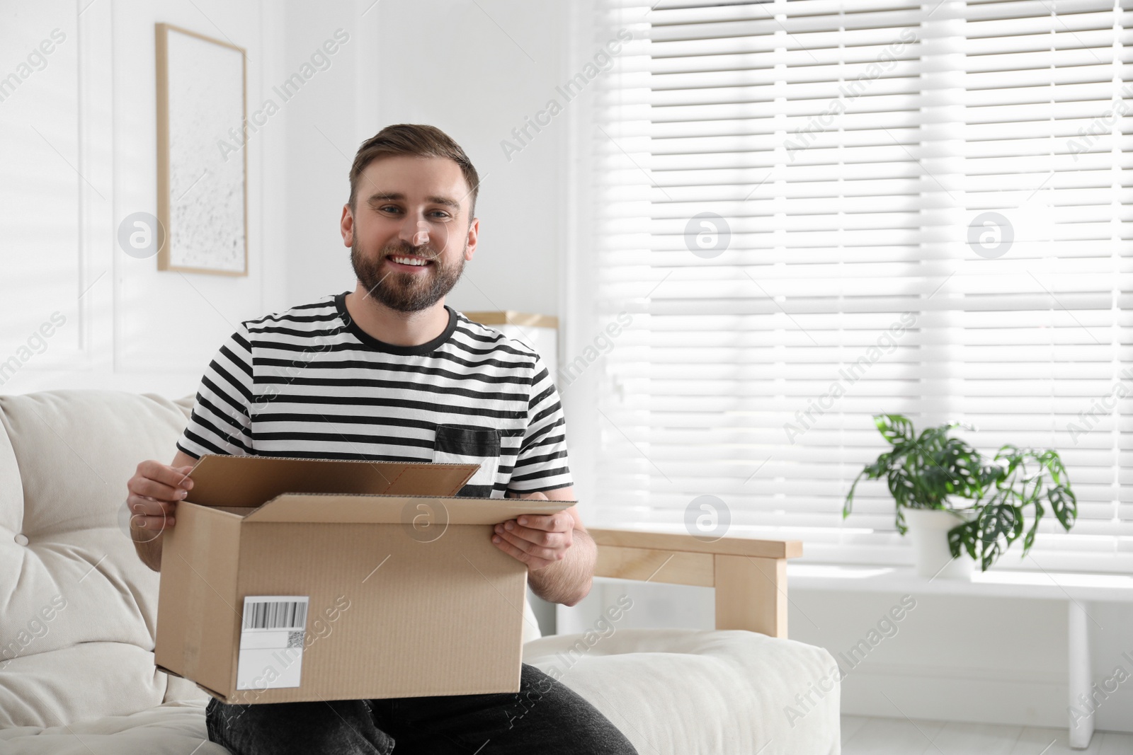 Photo of Happy young man with parcel at home