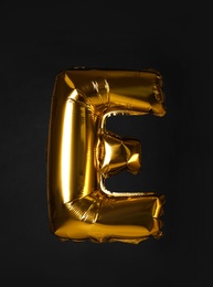 Golden letter E balloon on black background