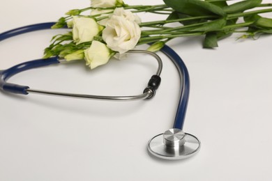 Photo of Stethoscope and eustoma flowers on white background. Happy Doctor's Day