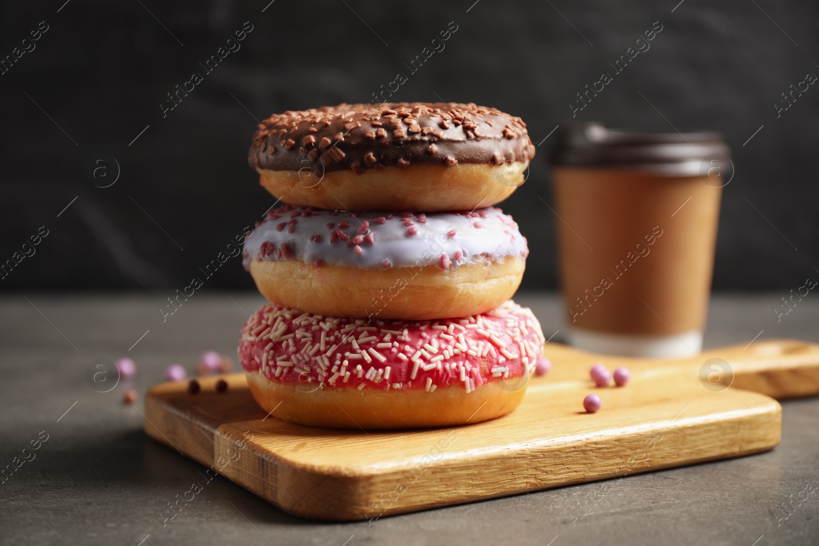 Photo of Sweet delicious glazed donuts on grey table