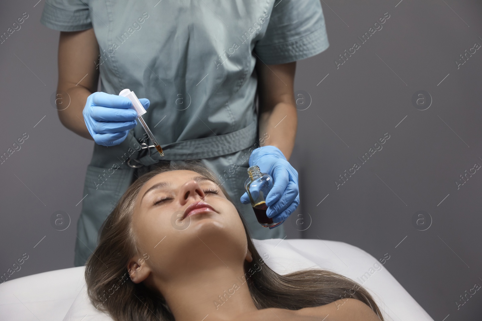 Photo of Cosmetologist applying serum on client's face in salon