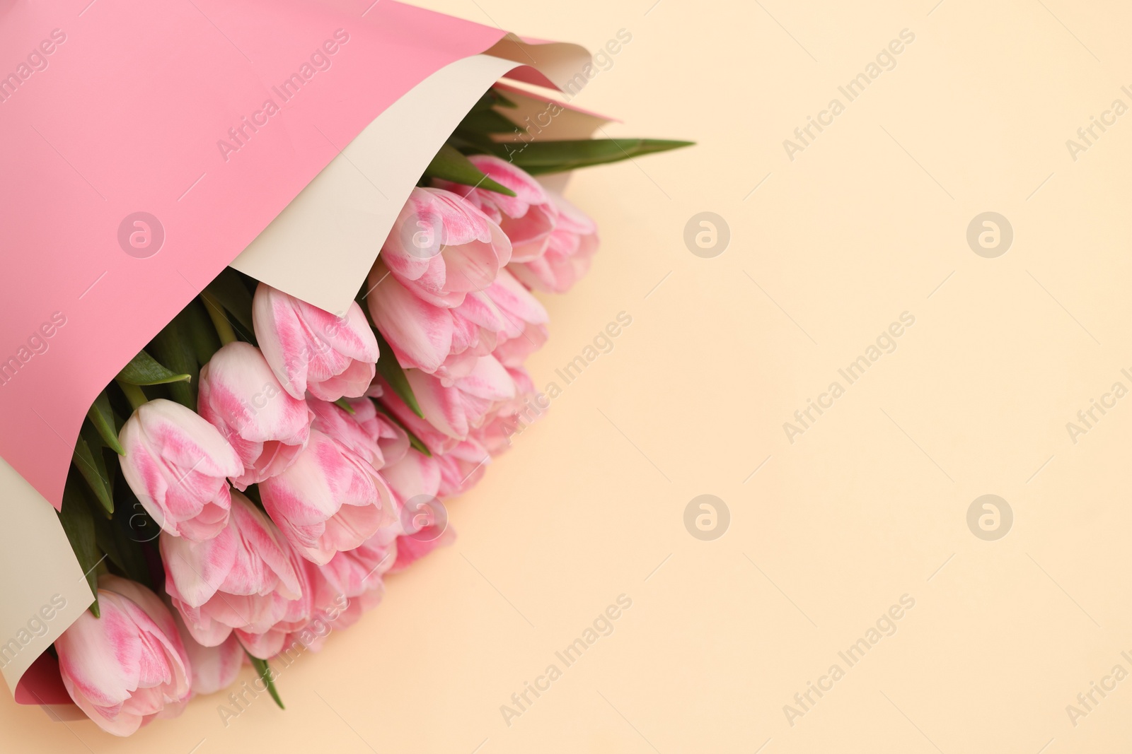 Photo of Beautiful bouquet of fresh pink tulips on beige background, top view. Space for text