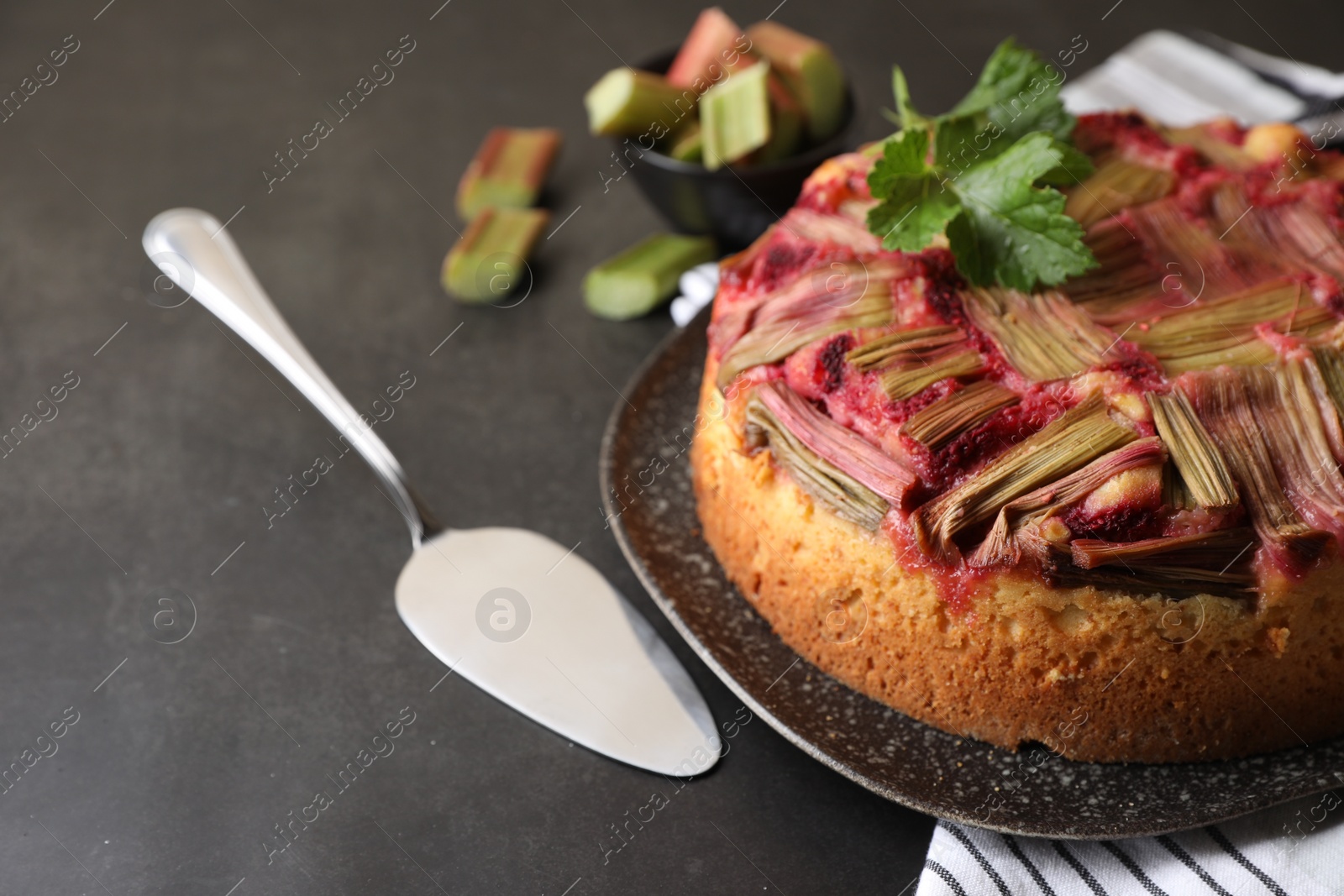 Photo of Freshly baked rhubarb pie and cake server on black table, closeup. Space for text