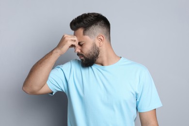 Young man suffering from headache on light grey background