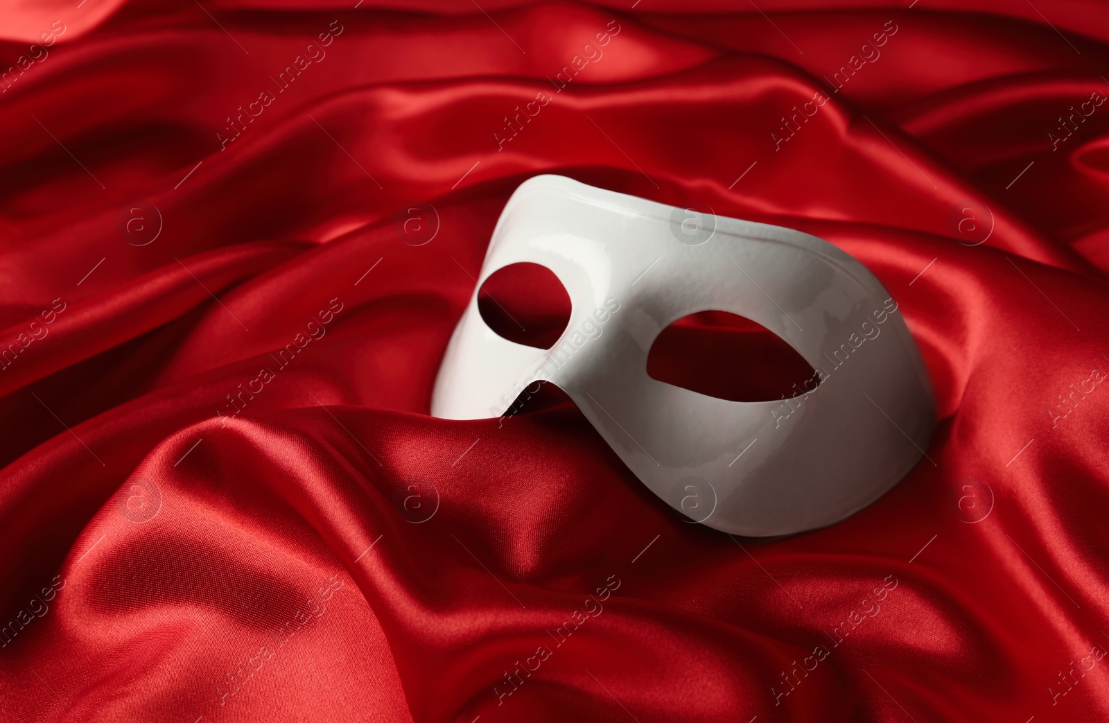 Photo of White plastic theatre mask on red fabric