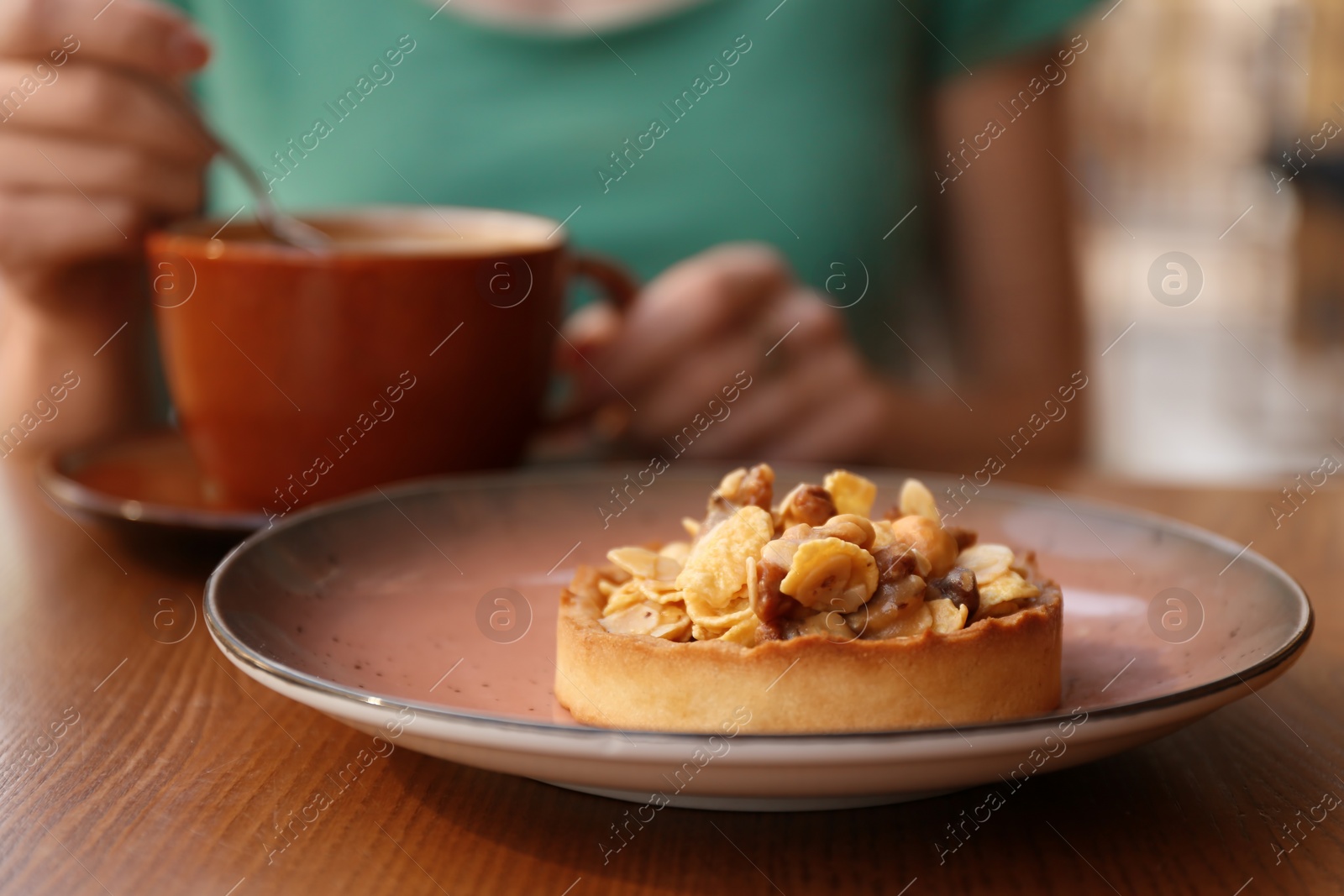 Photo of Plate with delicious cake and blurred woman on background