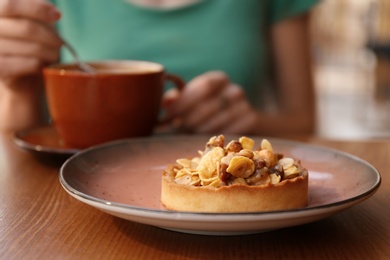 Plate with delicious cake and blurred woman on background