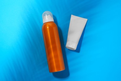 Photo of Sunscreens on light blue background, flat lay. Sun protection care